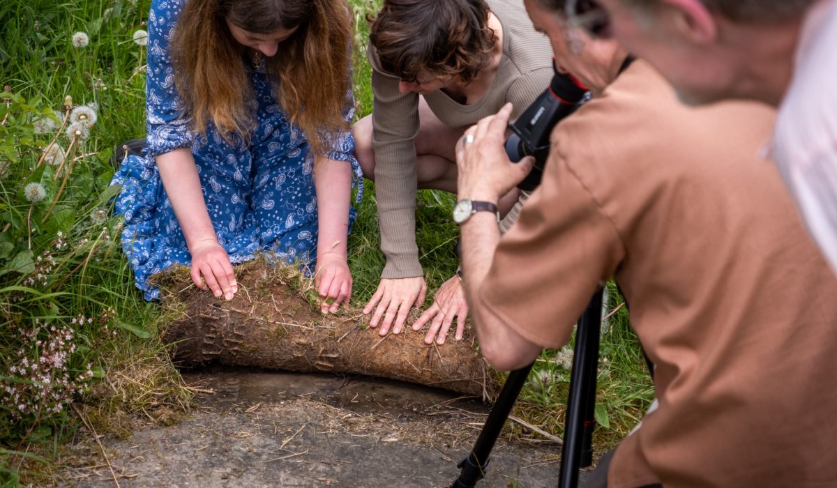 People peeling back the soil outside Goodshaw Chapel to find root bound inscriptions from gravestones